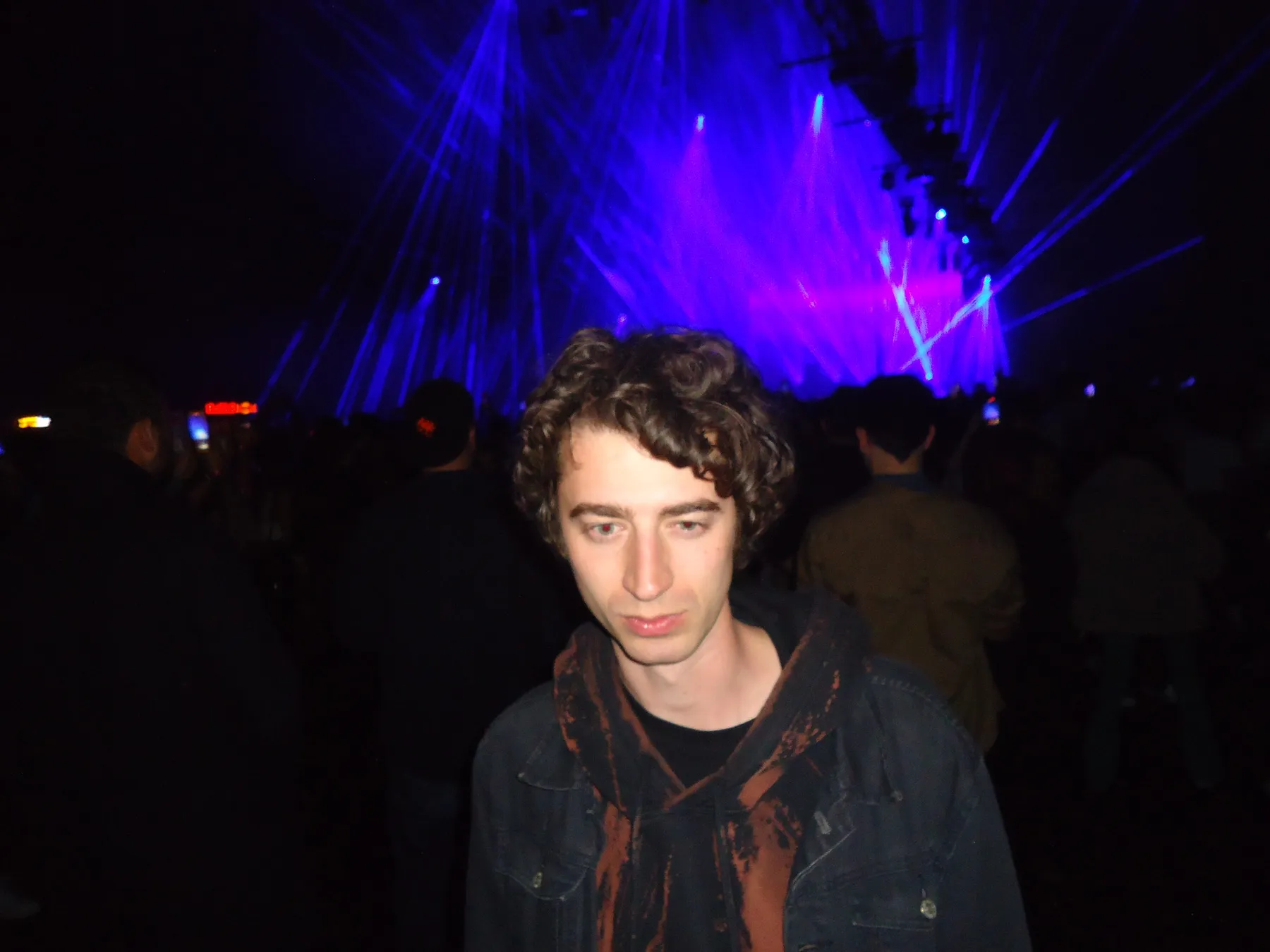 Young man with curly hair at a concert under blue lights