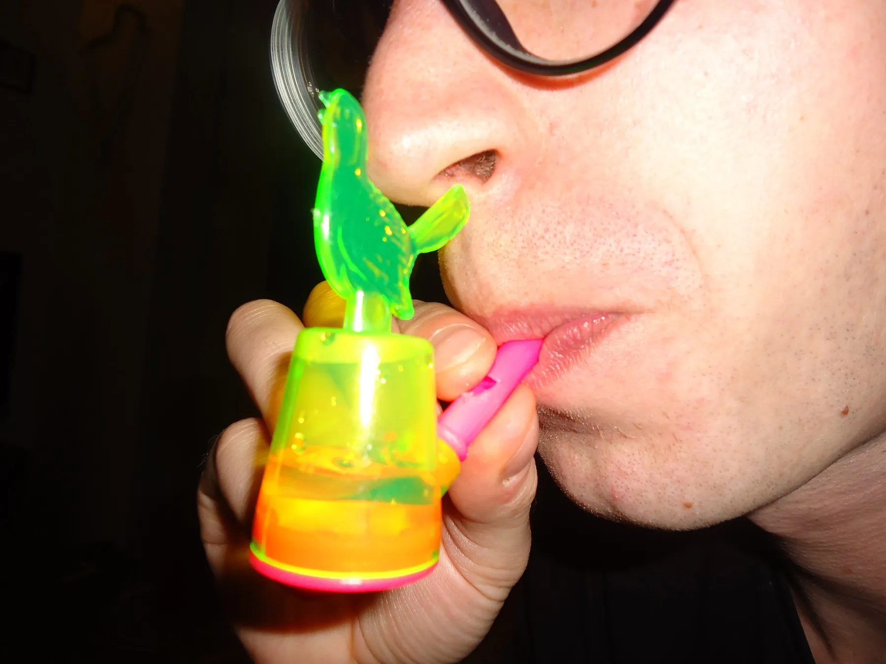 Close-up of a person blowing into a green plastic toy