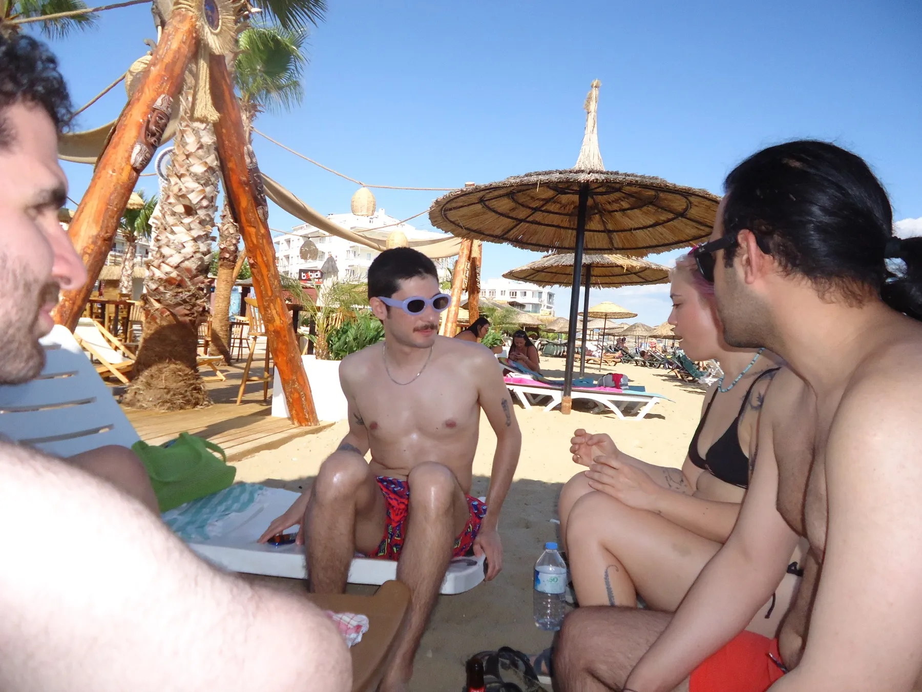 Friends sitting on a beach under straw umbrellas