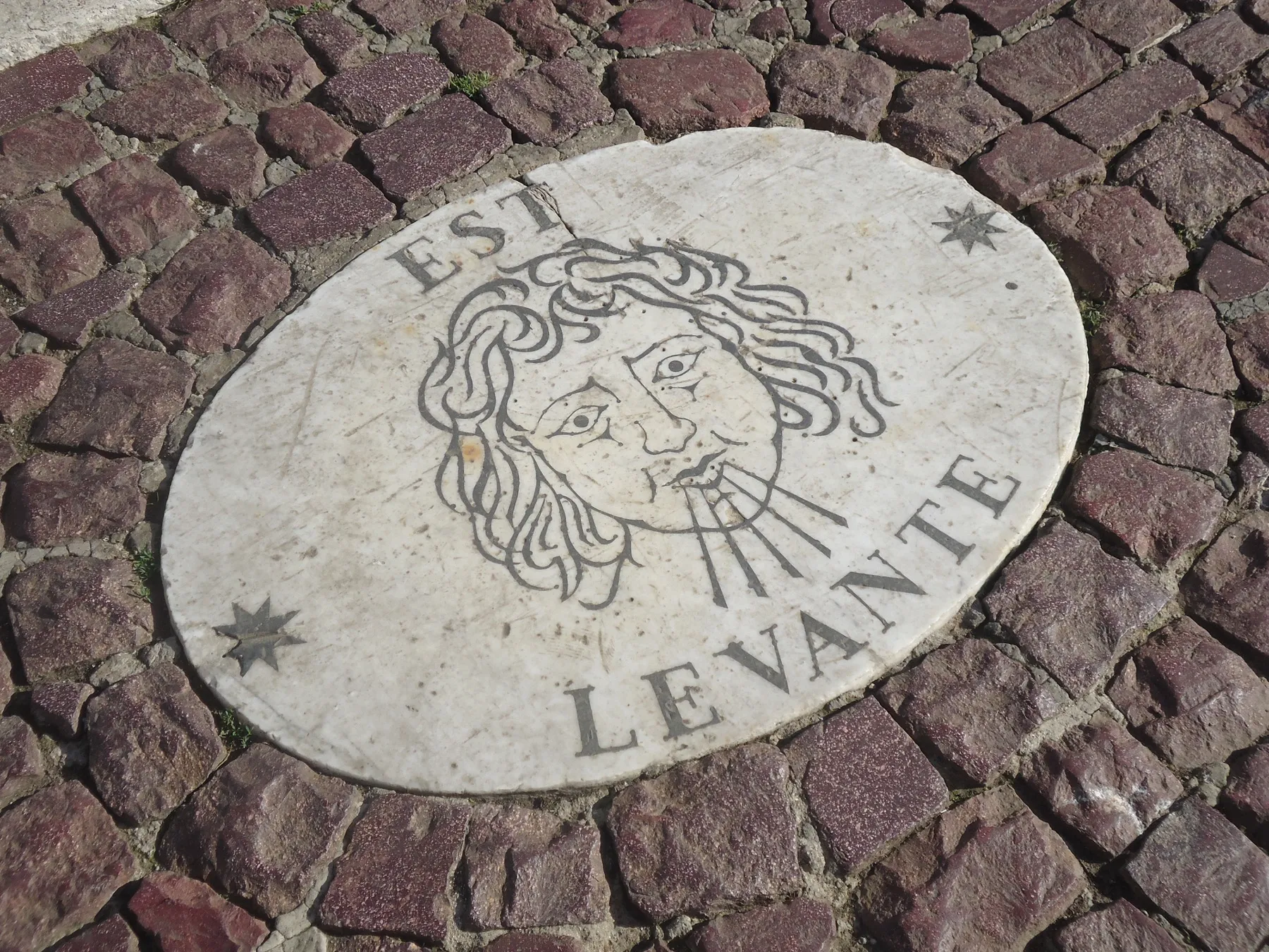 Stone wind-rose marker reading “Levante” set in cobblestones