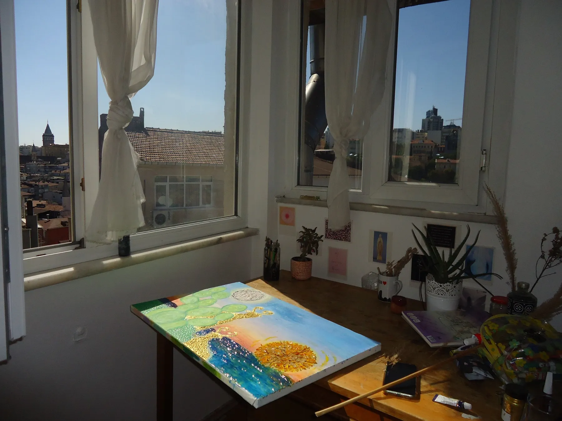 The same painting on a table by a window overlooking the city
