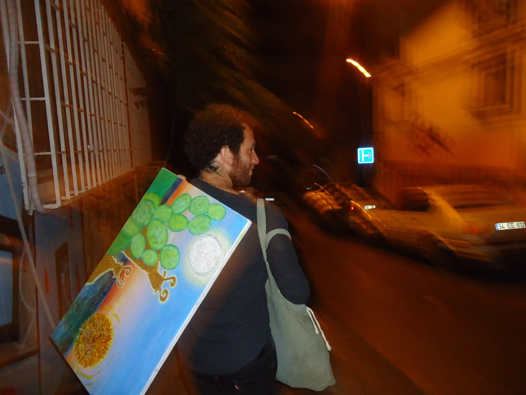 Man carrying the painting along a street at night