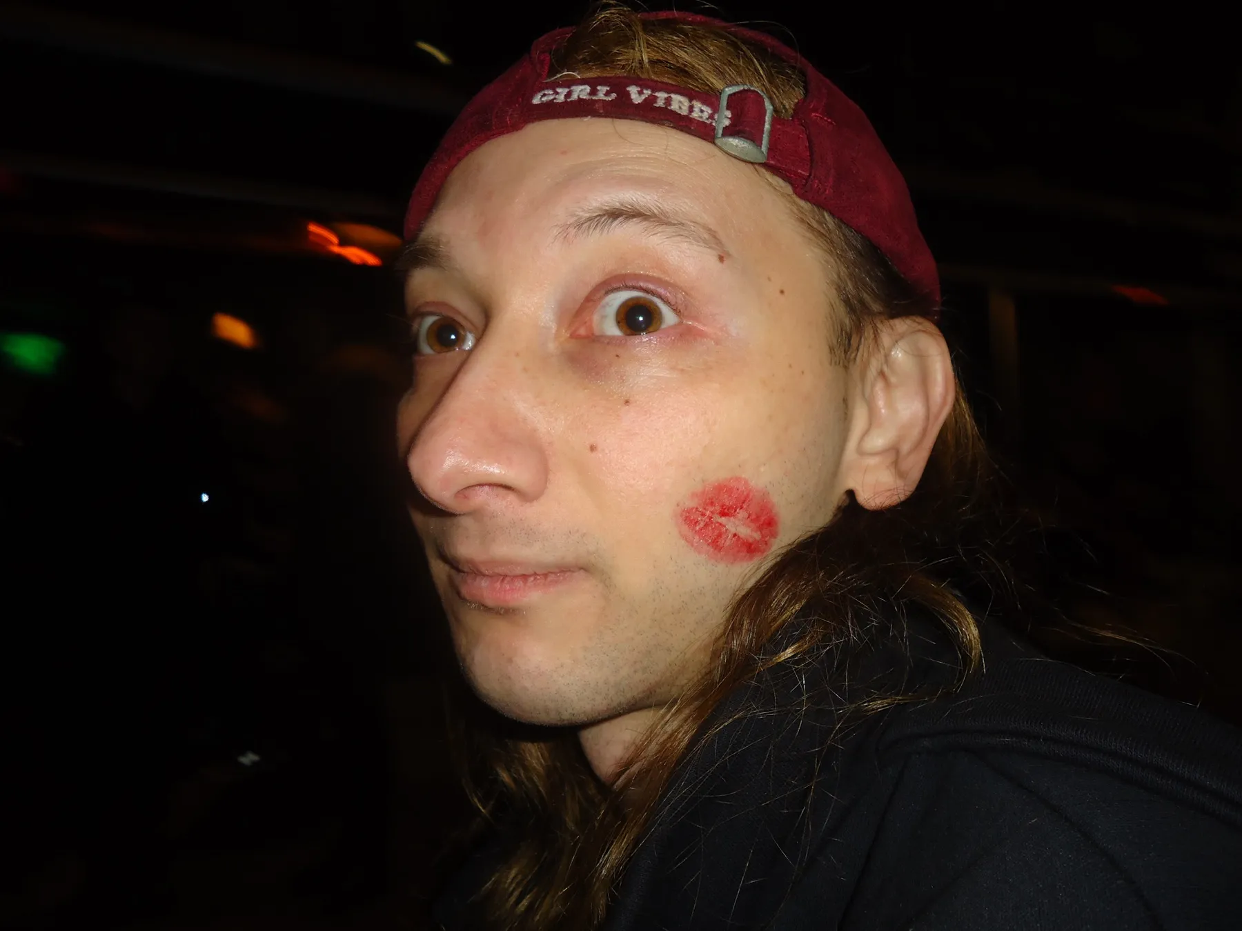 Person in a red cap with a lipstick kiss on the cheek