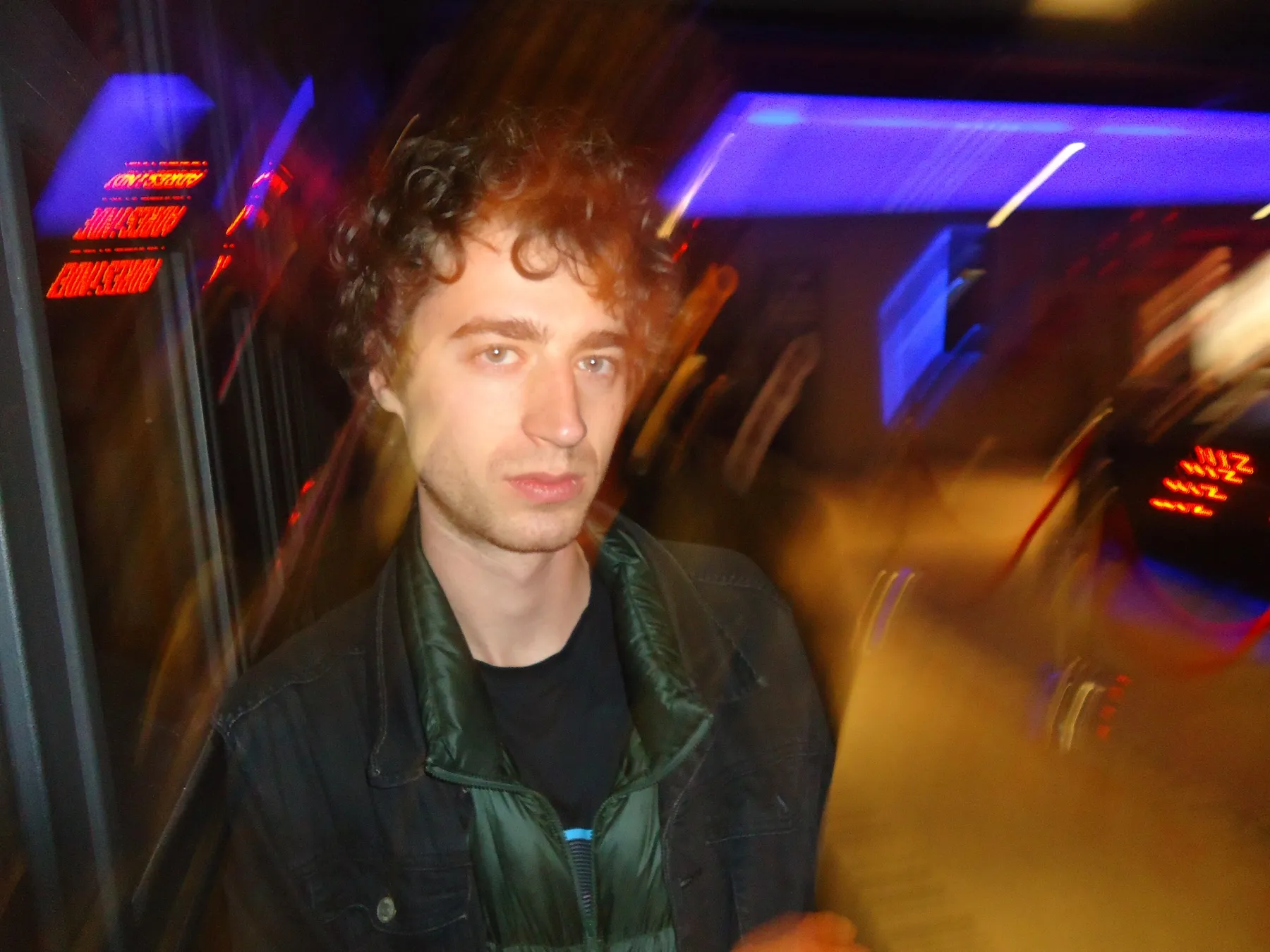 Young man blurred by motion under neon lights