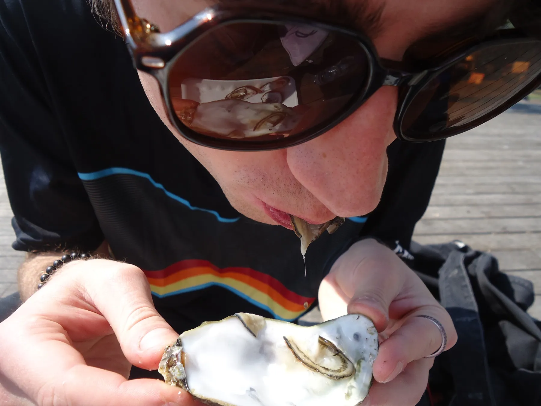 Person in sunglasses eating an oyster