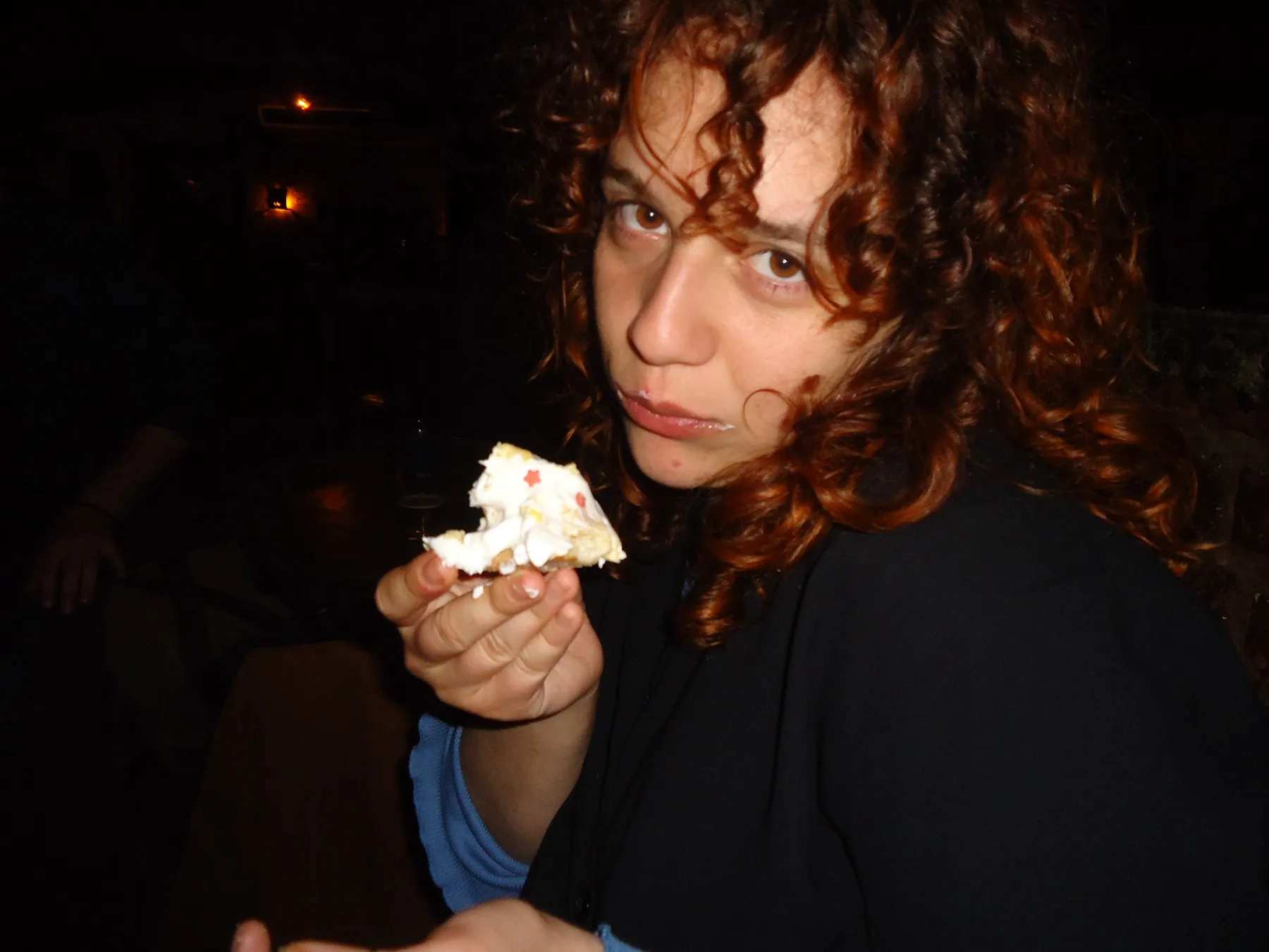 Woman with curly hair holding a piece of cake