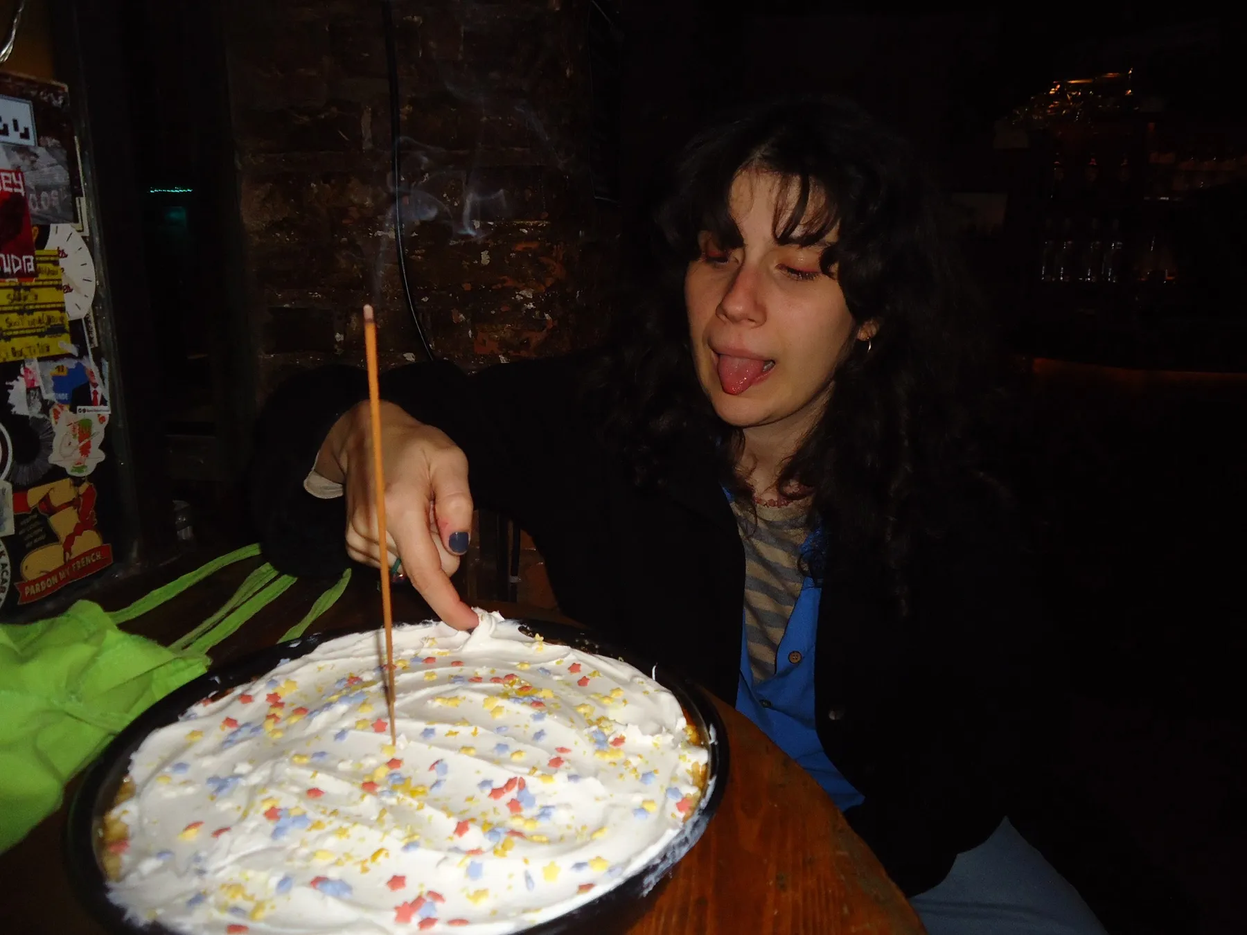 Woman sticking out her tongue beside a cake