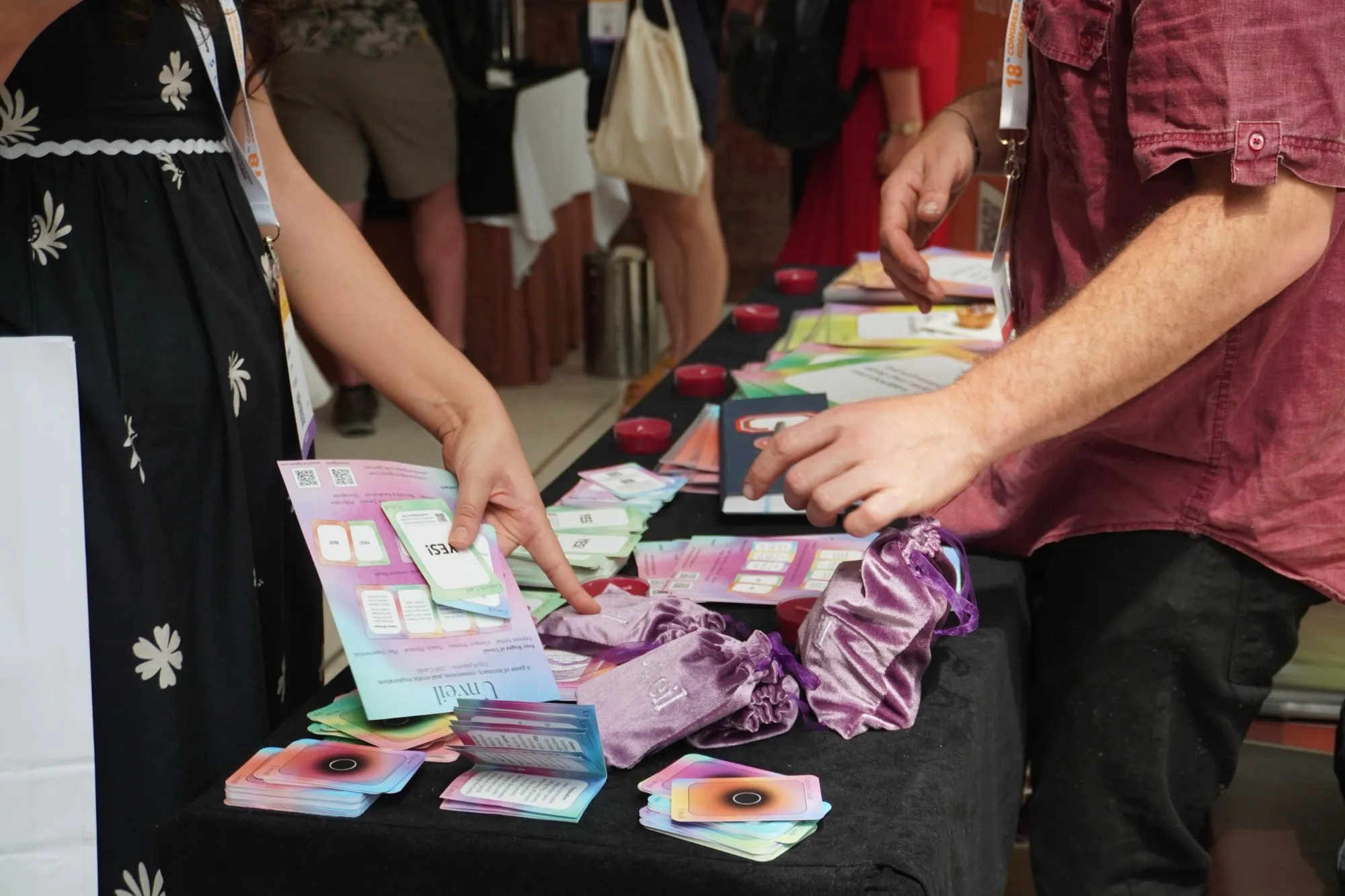 Two people pointing at Unveil cards, leaflets and velvet bags on a table