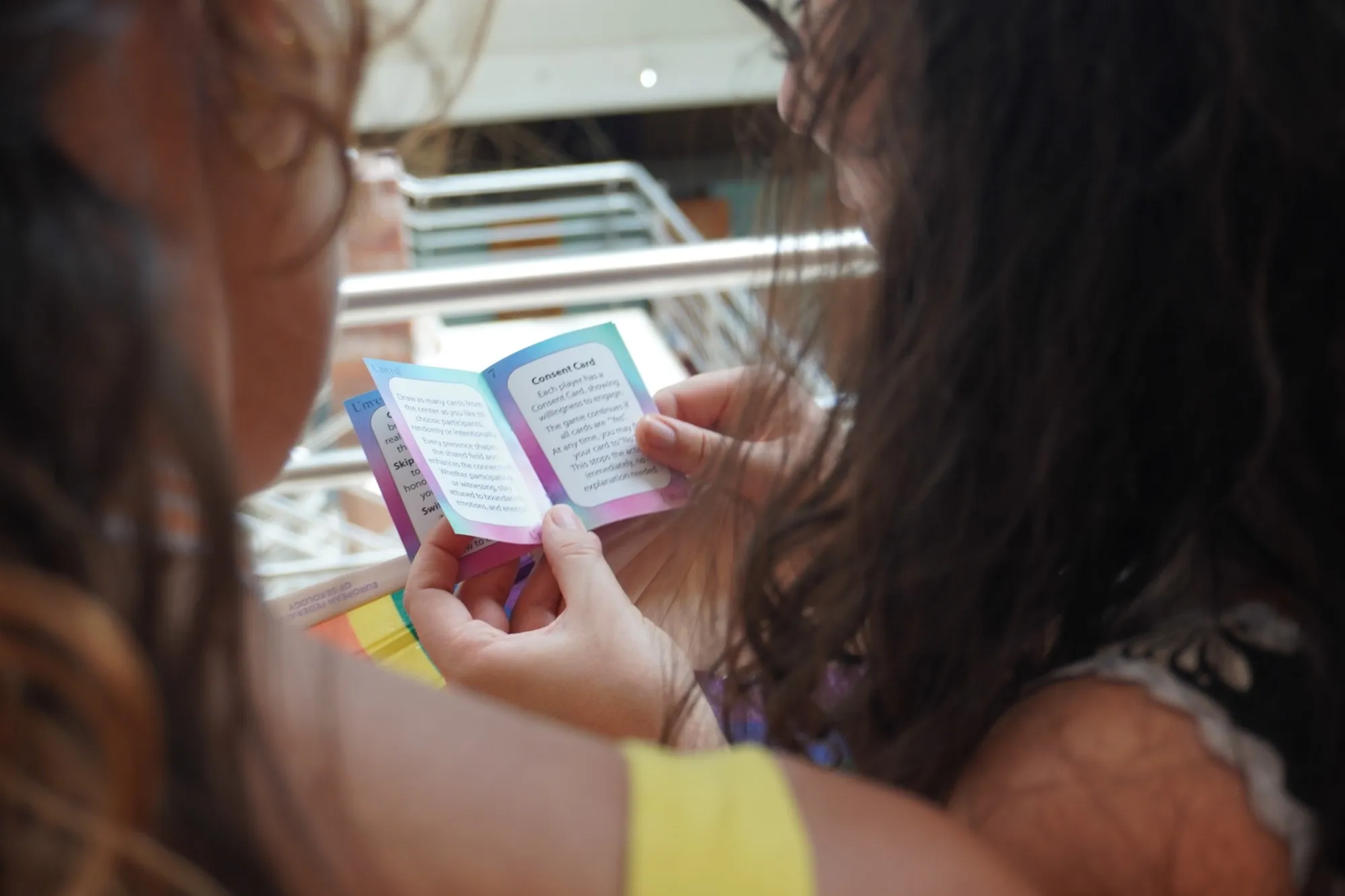 Two people reading the small Unveil rule booklet about the consent card