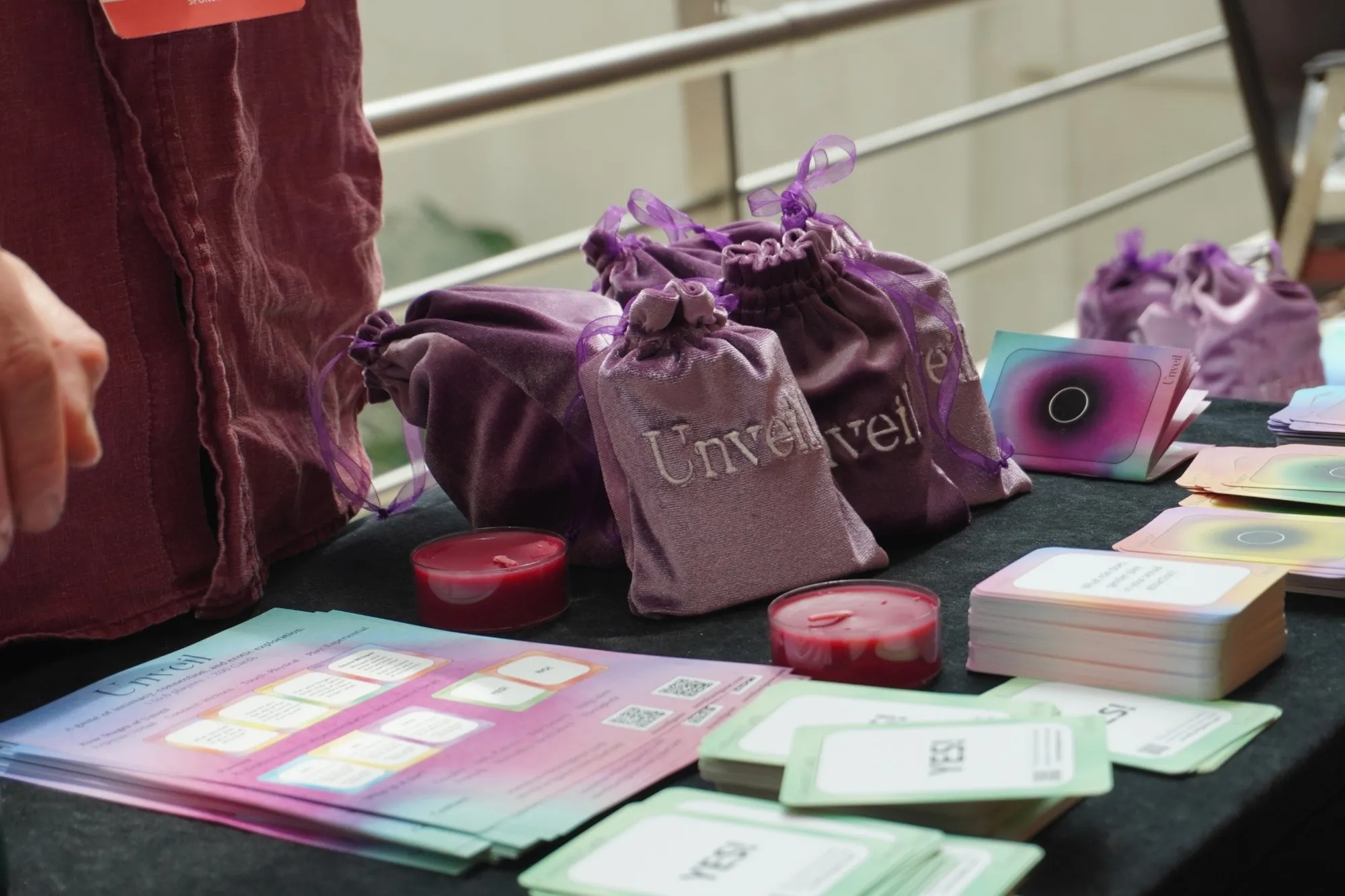 Purple velvet Unveil bags, candles and card decks on a table